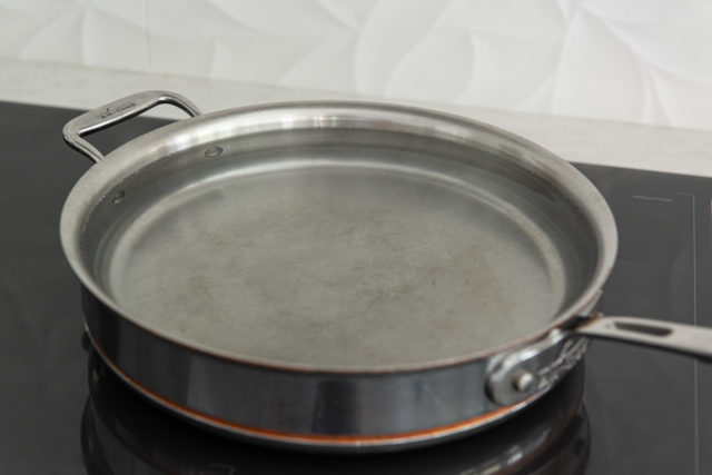 Shallow Saucepan with Hot Water on Induction Cooktop