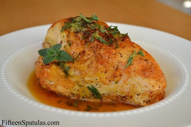 Split Chicken Breast - Roasted and Sprinkled with Herbs and Served on White Plate