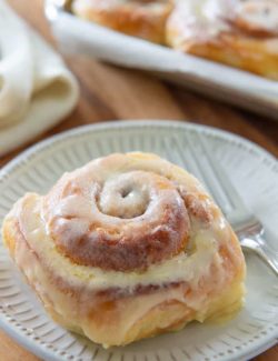 Cinnamon Rolls - On a White Plate with Butter Icing on Top and Fork