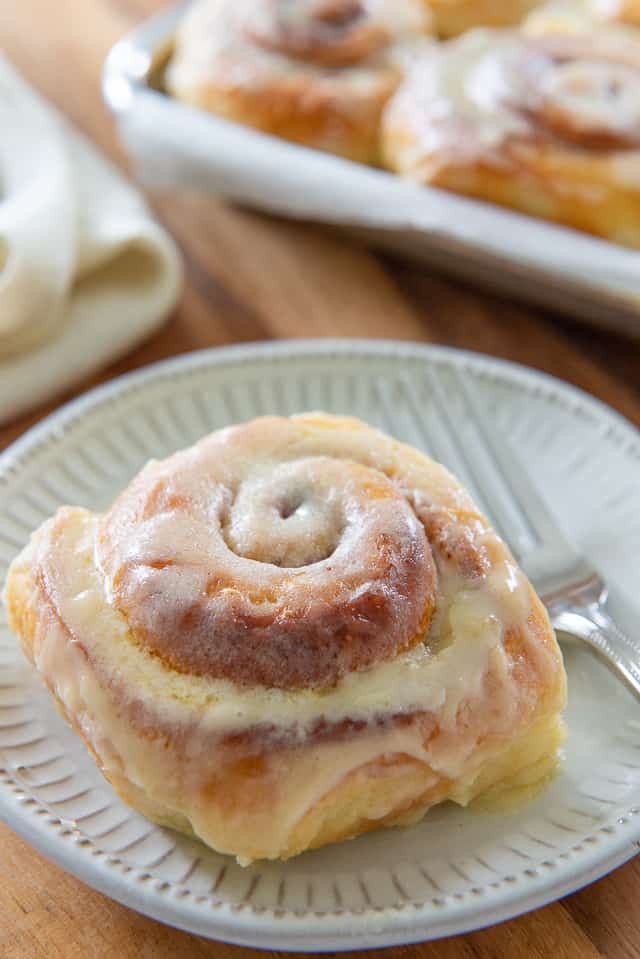 Overnight Cinnamon Rolls - On a White Plate with Butter Icing on Top and Fork