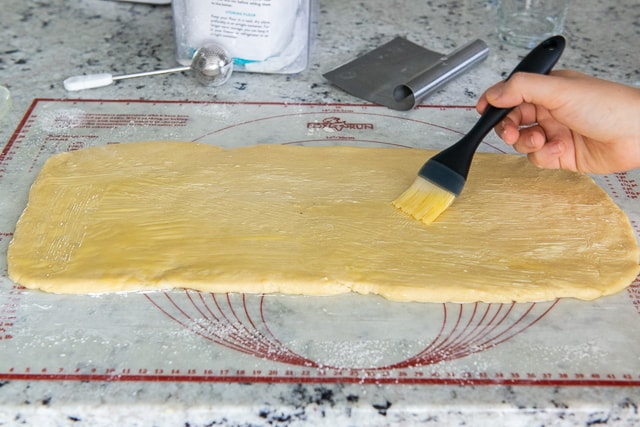 Brushing rolled out dough rectangle with butter before filling