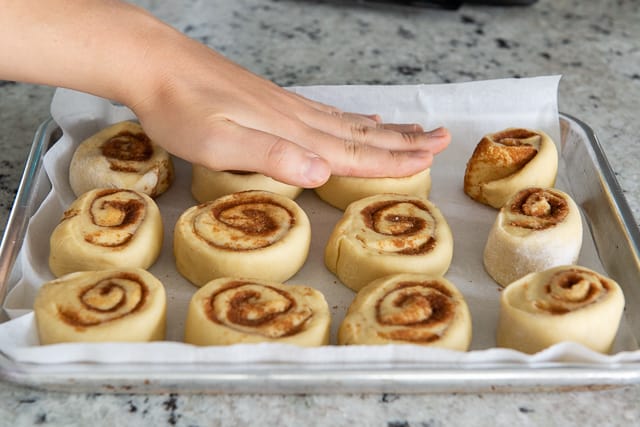 Flattening the Cut Cinnamon Rolls With Palm of Hand