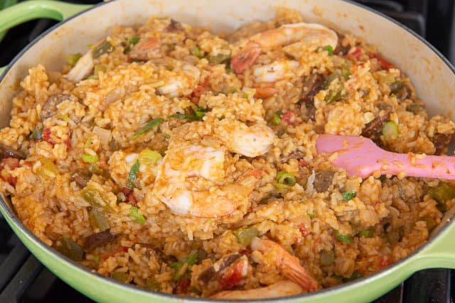 Best Jambalaya Recipe In Green Braiser Dish with Green Onion, Shrimp, and Smoked Andouille Sausage