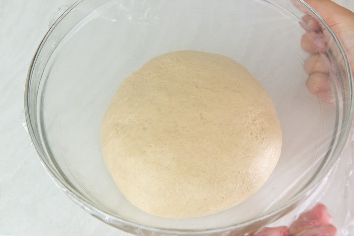The Dough Rolled Into a Bowl and Covered with Plastic Wrap