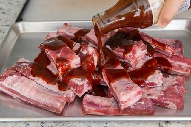 Pouring BBQ Sauce on Spare Ribs Before Going In Oven