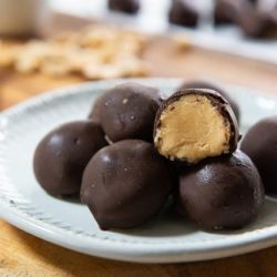 Peanut Butter Balls Stacked on a White Plate with Filling Shown