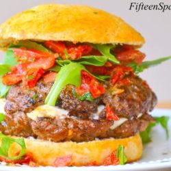 Caprese Burger - Shown on a Plate with Mozzarella Cheese Oozing from Center and Tomato Basil Relish on Top