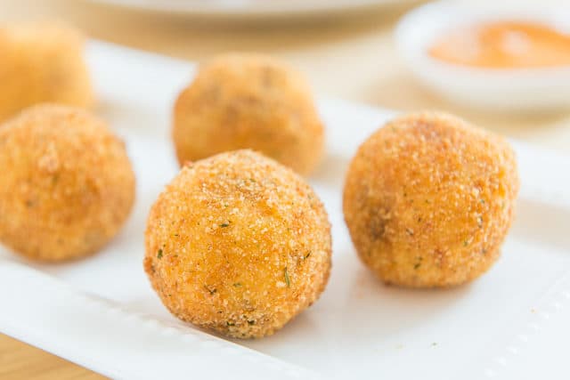 Potato Croquettes Recipe - Served On a White Platter with Dipping Sauce in background