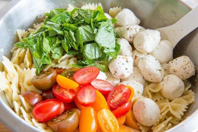 Mozzarella balls, basil, and tomatoes with pasta bowties in bowl