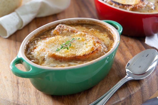 Homemade French Onion Soup - in green ovenproof dish and broiled cheese crouton topping