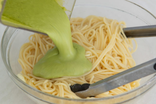 Pouring Green Chile Sauce Onto Spaghetti