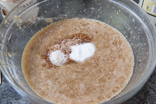 Pureed Banana Wet Ingredients in Glass Bowl with Cinnamon, Nutmeg, and Leavening On Top