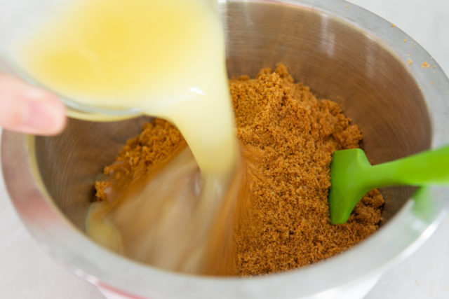 Pouring Melted Butter Into a Bowl with Ground Gingersnap Cookie Crumbs
