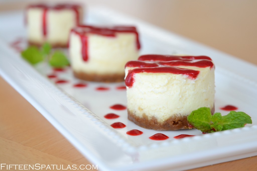 Individual Cheesecakes on White Platter with Raspberry Sauce Drizzle