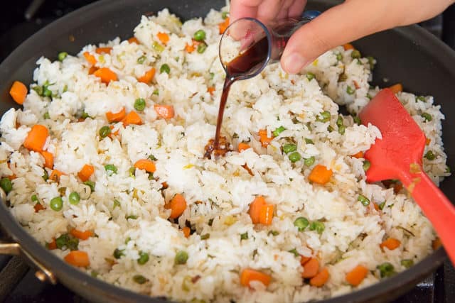 Pouring Soy Sauce Over Rice with peas and Carrots