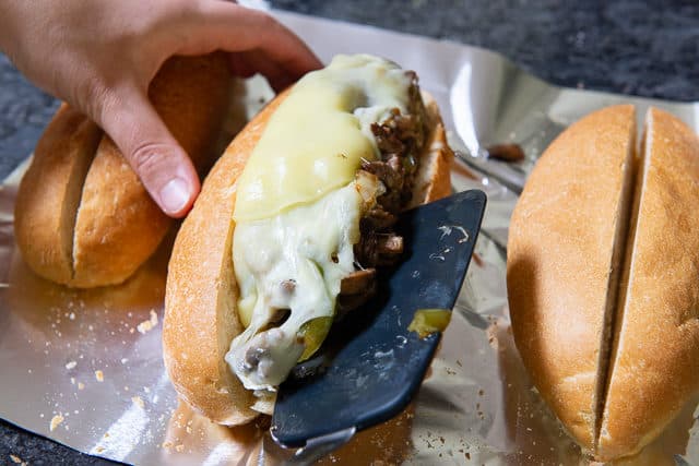 Spooning Philly Steak Sandwich Filling Into Hoagie Roll