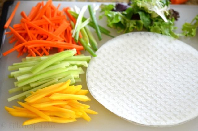 carrots, cucumber, scallions, mango, lettuce for spring rolls on cutting board