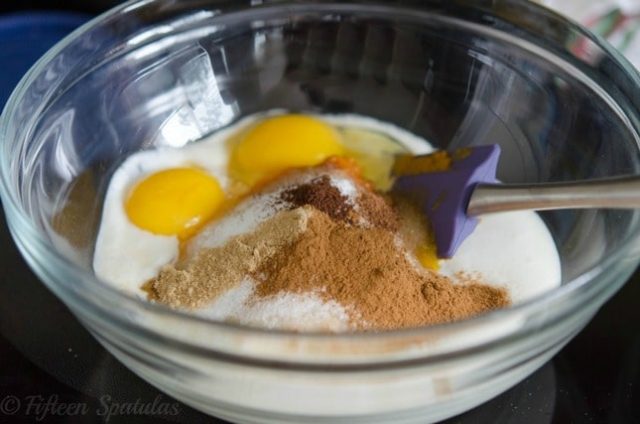 canned pumpkin pie ingredients in a mixing bowl with eggs, spices, etc