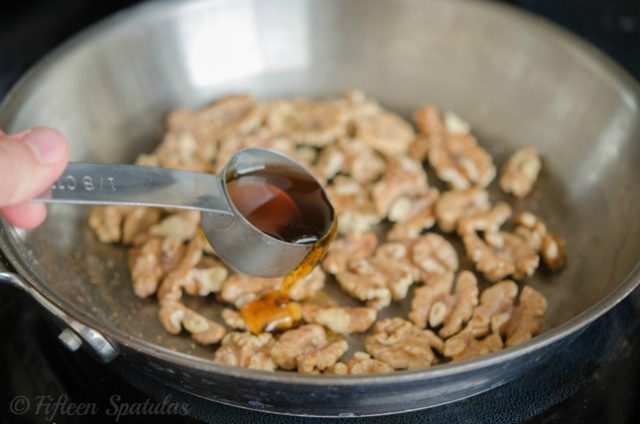 glazing walnuts with maple syrup in stainless skillet