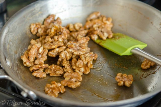 Candied Walnuts Maple Syrup Glaze in Stainless Steel Skillet with Green Spatula