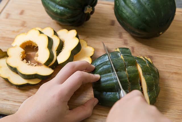 Cutting the Acorn Squash Into Slices on Wooden Board