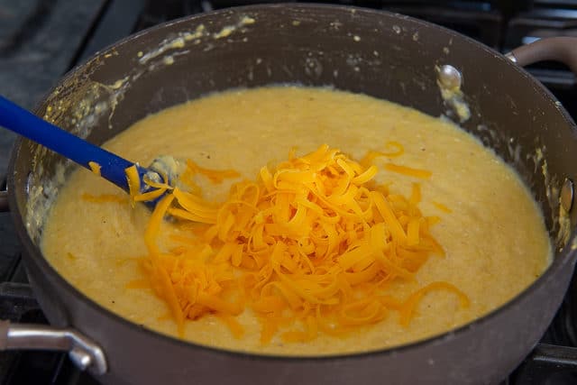 Shredded Cheddar Cheese Added to Grits in Pan