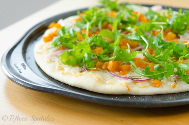 butternut squash pizza - topped with red onion, arugula, rosemary, and cheese