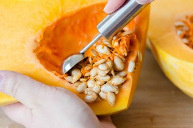 using a melon baller to remove the seeds and strings from butternut squash