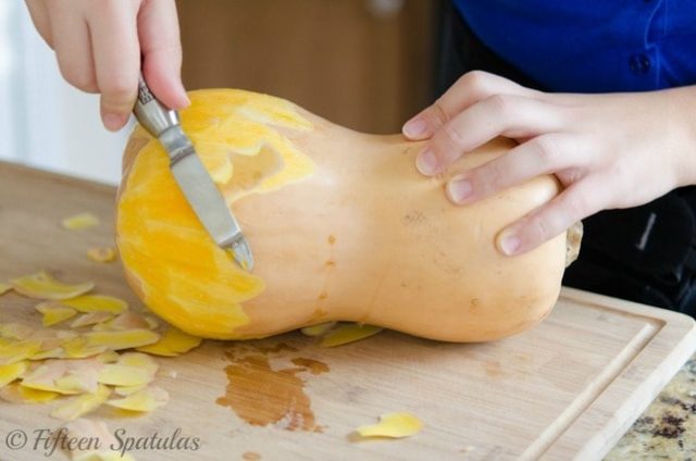 peeling a butternut squash with a vegetable peeler for pizza