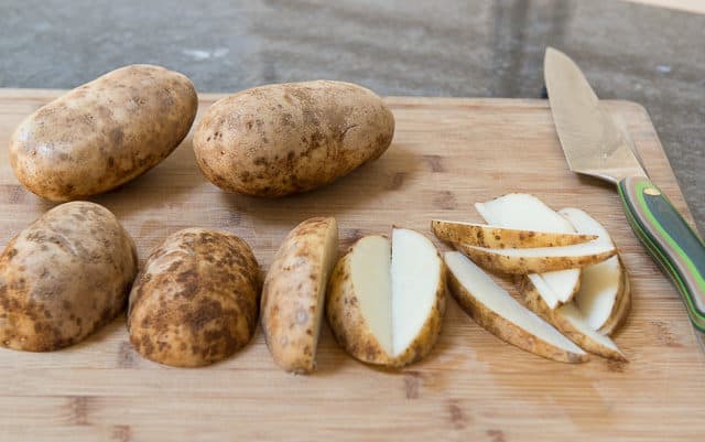 Cutting Russet Potatoes into Wedges on Board