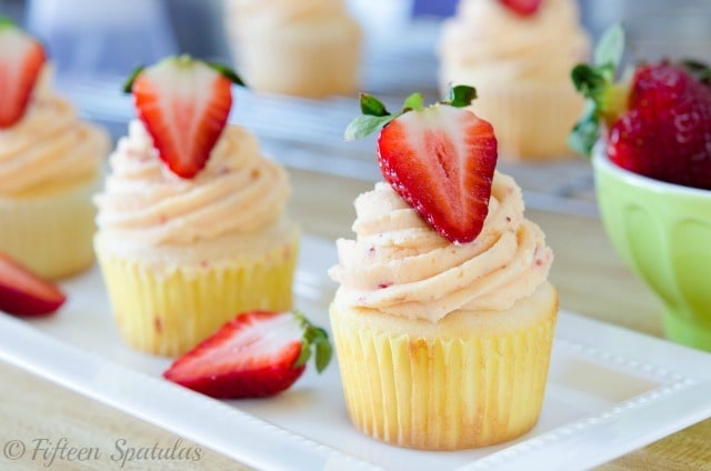 white cupcakes with a fresh strawberry buttercream piped on top