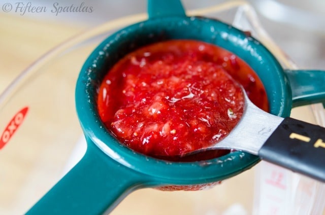 a strainer with strained macerated strawberries