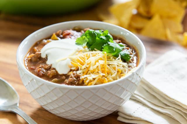 Turkey Chili Recipe - Garnished with Sour Cream, Shredded Mexican Cheese Blend, and Fresh Cilantro Leaves