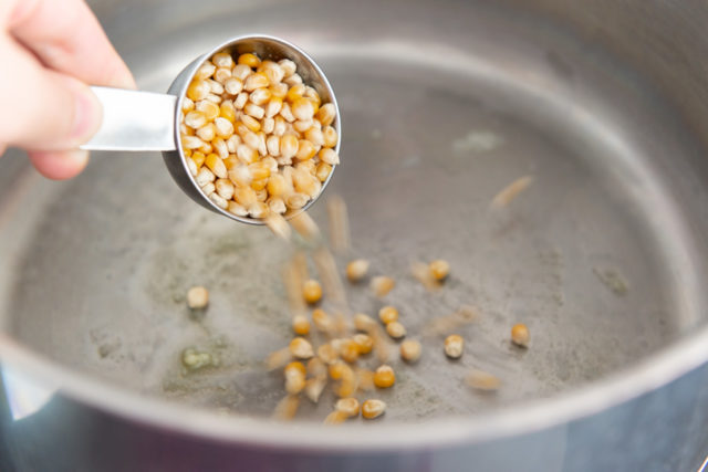 Adding popcorn kernels to the stainless steel pan