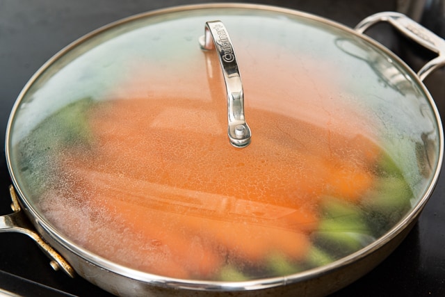 Cover with a Lid to Help Cook Faster, as shown here with carrots enclosed