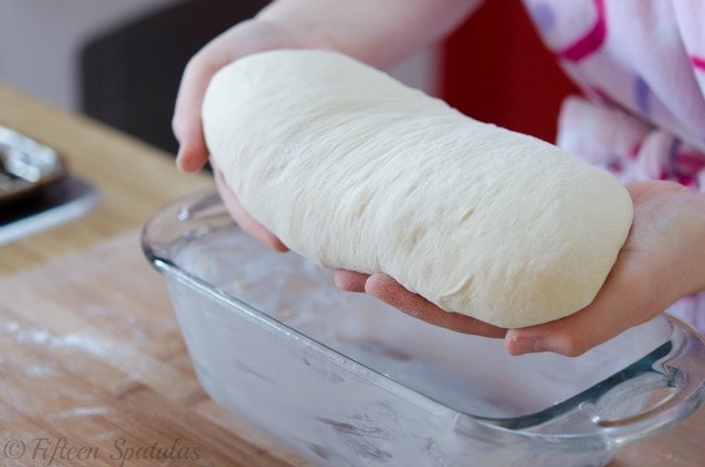 placing a roll of sandwich dough into a loaf pan