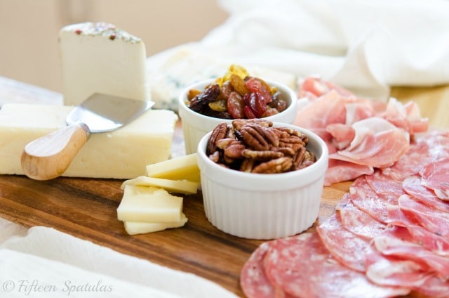 Cheese pairings - Shown on Cutting board with three cheeses, meats, and fruit