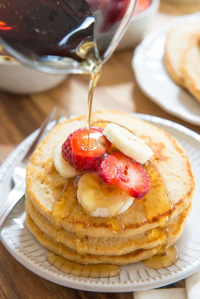 Whole Wheat Pancakes - Stacked On a Plate with Maple Syrup Pouring Over The Top