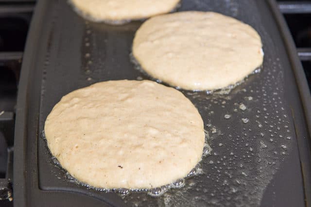 Partially Cooked Circles of Pancake Batter on a Buttered Griddle