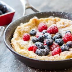 Dutch Baby Pancake Topped with Fresh Raspberries and Blueberries in a Skillet
