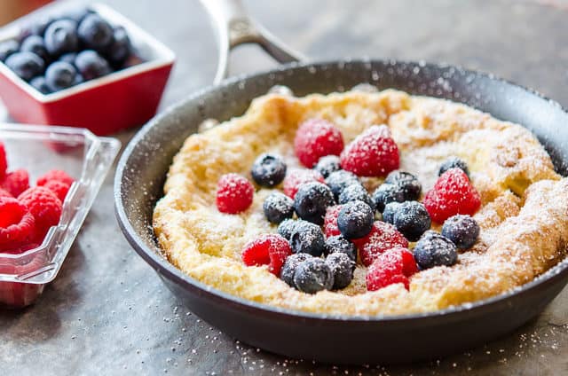Dutch Pancake Recipe Served in Skillet with Powdered Sugar and Berries On Top