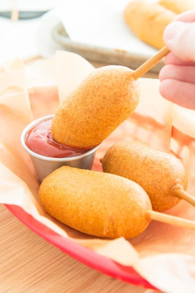 Homemade Corn Dogs - In a Red Basket Dipping Into Ketchup