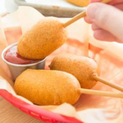 Homemade Corn Dogs In a Red Basket Dipping Into Ketchup