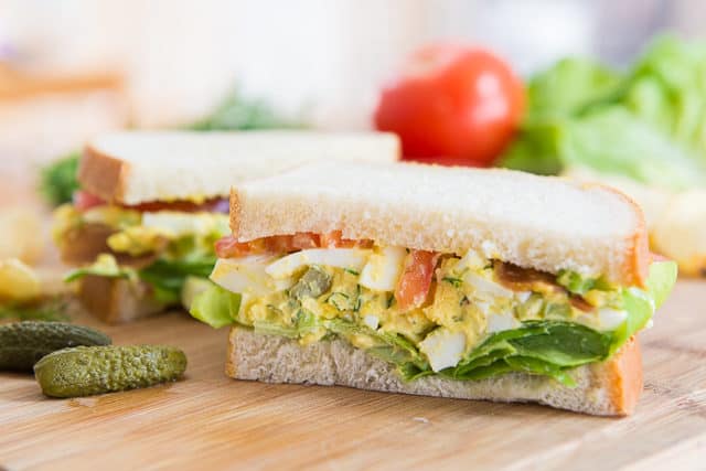Egg Salad Sandwiches on a Wooden Board with Pickle