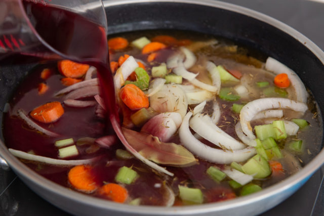 Pouring Wine Into Skillet with Vegetables and Broth