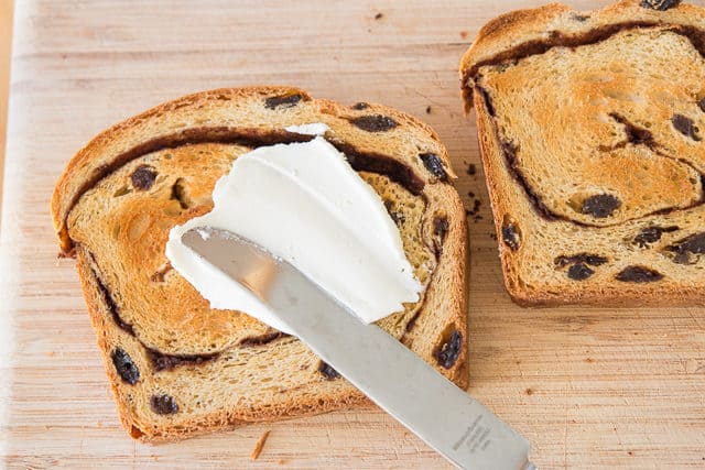 Raisin Toast Being Spread with Butter on a Wooden Board