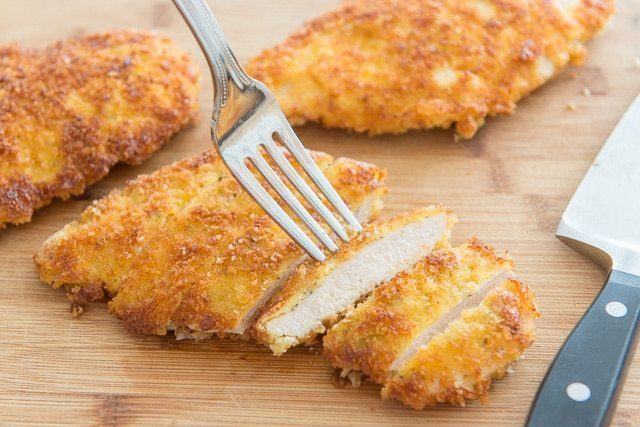 Parmesan Crusted Chicken Recipe - Served on a Wooden Board with Fork Showing One Slice