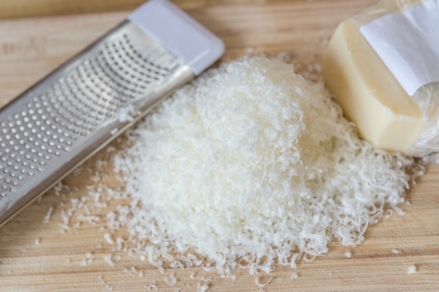 Shredded Parmesan Cheese on Wooden Board with Grater
