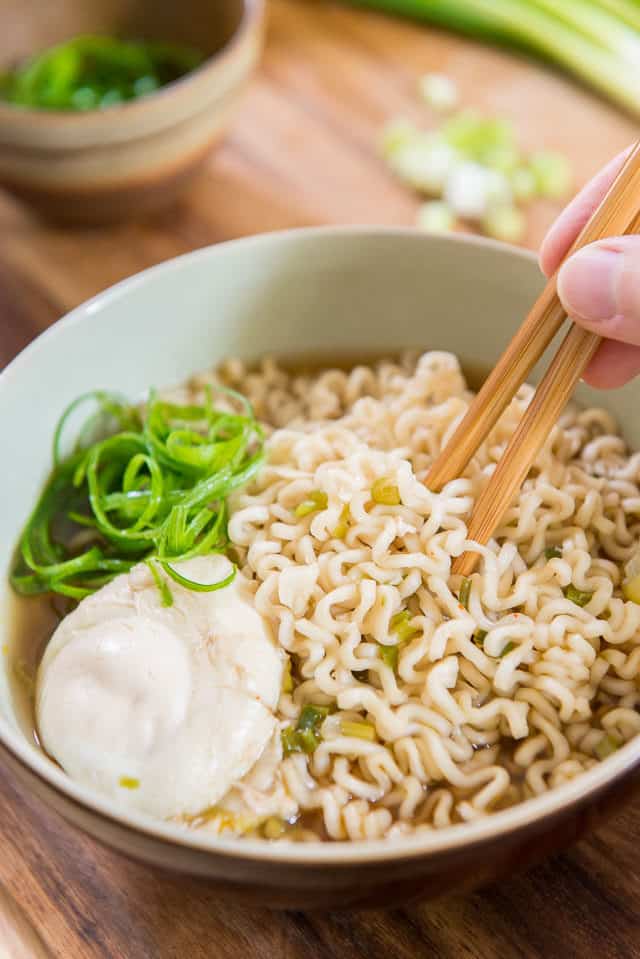 Ramen Soup - In Ceramic Bowl With Chopsticks, Curly Scallions Garnish, and Poached Egg