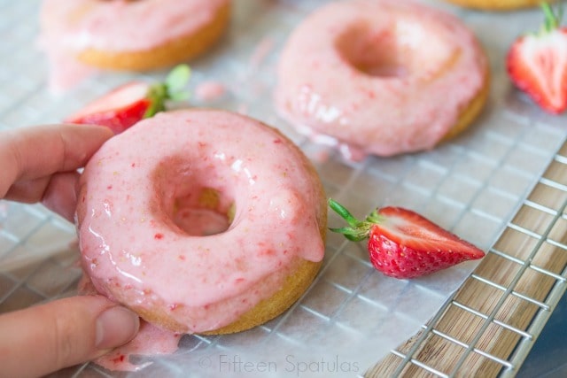 Holding Up a Strawberry Frosted Donut on Cooling Rack